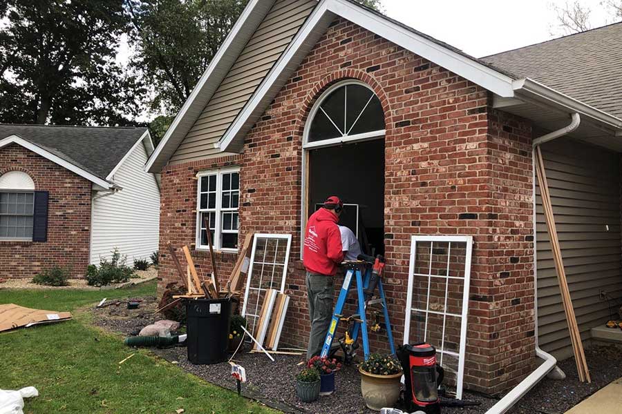 Window replacement experts installing a new pocket window on a residential brick and vinyl siding home in Springfield, IL.