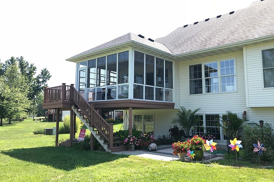 The backyard sunroom and deck with multiple windows, letting in sunlight in a residential home in Chatham, IL.