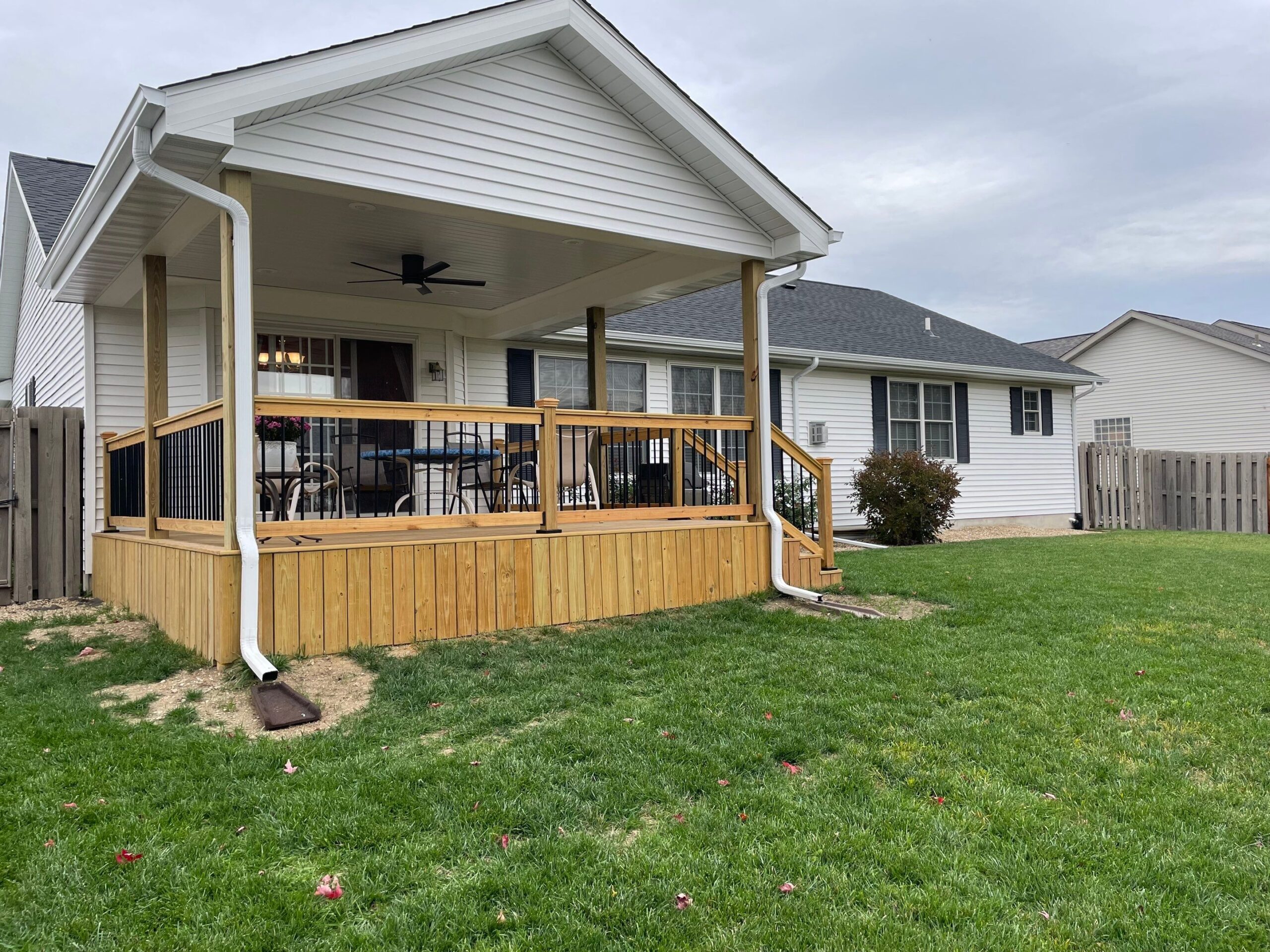 Oversized deck addition on a crawl built by Sutton’s, matching the height of a single-story home with walk-out access from a sliding patio door, featuring a gabled roof and decorative railing