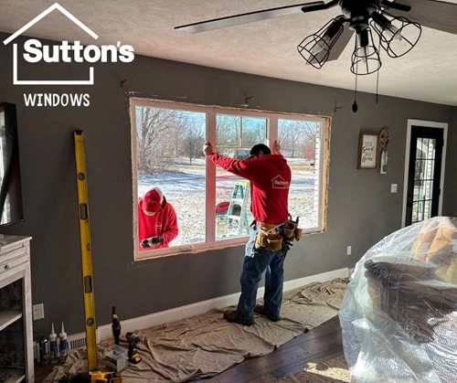 Two Sutton’s window installers working together on the same window installation, one holding the window in place from inside and the other working from the outside in Springfield IL